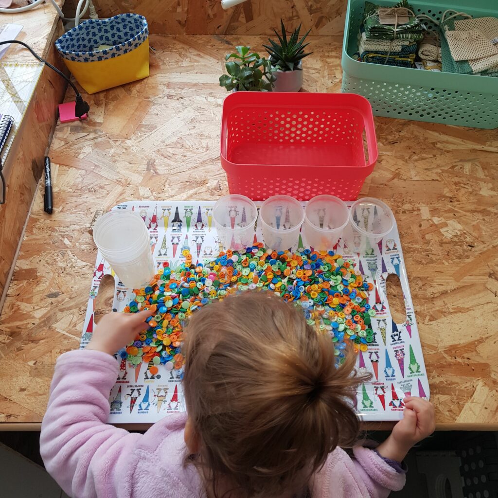 Photo d'un enfant triant des boutons pression par couleur