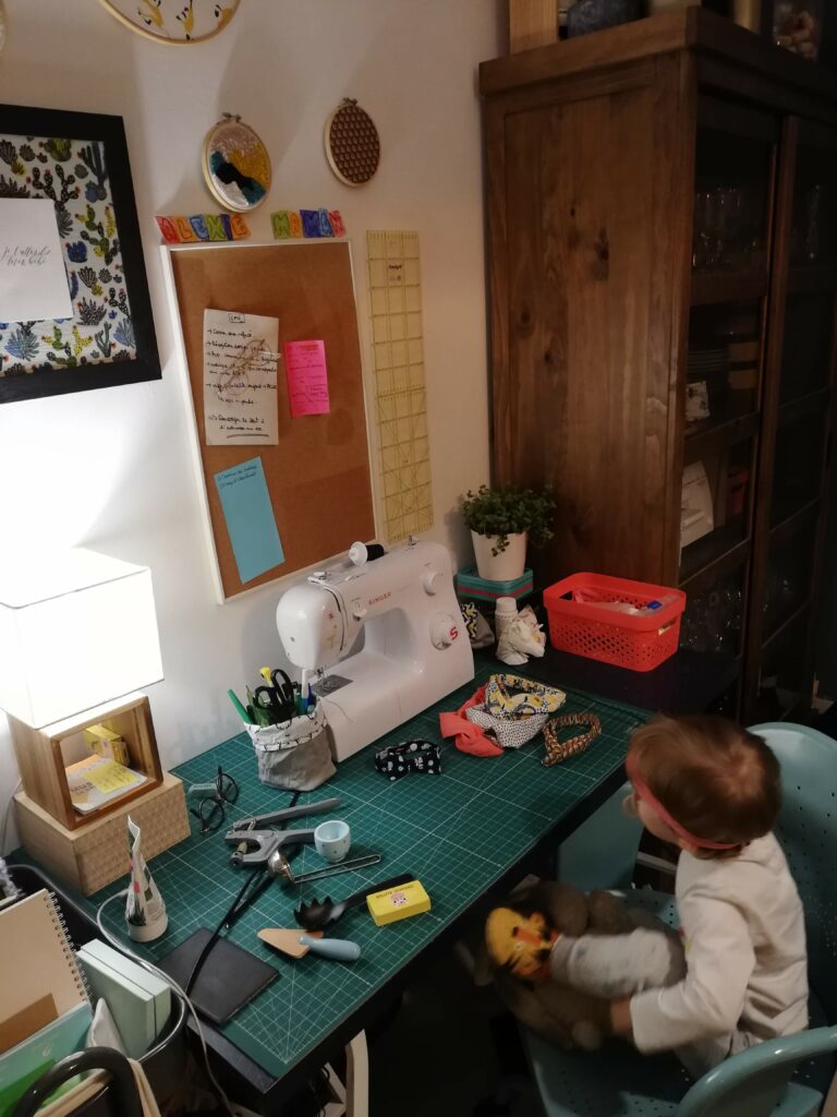 mon nouveau blog : une petite fille assise devant une table avec une machine à coudre et du matériel