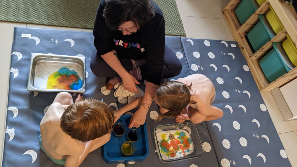 Photo d'une maman faisant une activité avec ses enfants en utilisant des colorants, du bicarbonate et du vinaigre.