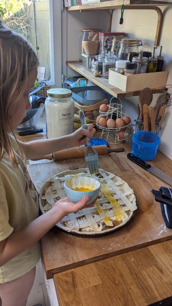 enfant qui badigeonne de l'oeuf sur une quiche