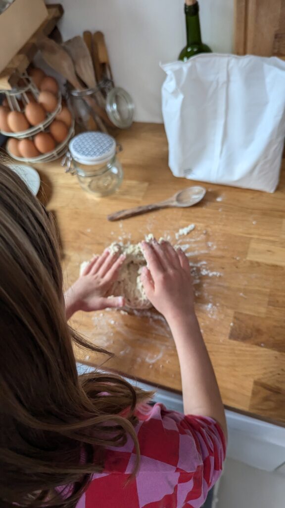 Enfant qui pétrie une pâte à pain à la main.