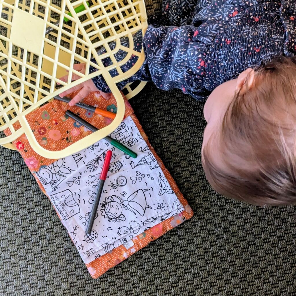 Photo d'un enfant avec devant lui un cahier d'activités lavable de la sardine verte ouvert sur un coloriage de princesses. Deux feutres à l'eau sont posés sur le cahier.